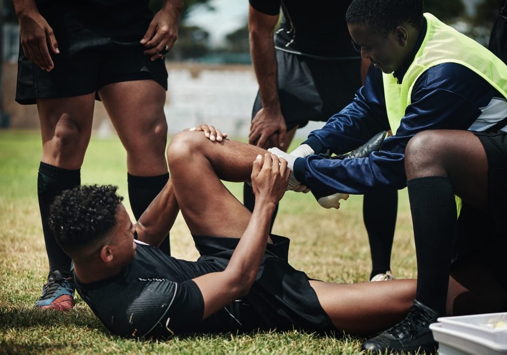 Cropped shot of a young rugby player receiving first aid assistance on the field.